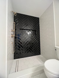 a black and white tiled shower with a toilet