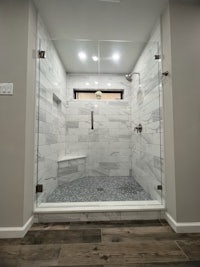 a bathroom with a glass shower stall and hardwood floors